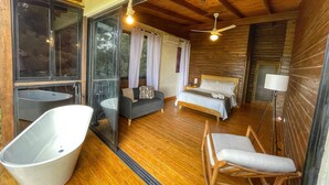 A modern interior with a large bathtub, a sofa, a bed, and a ceiling fan. - Escápate al Bosque · Villa Completa · Piscina · BBQ · Hasta 12 Huéspedes (Jarabacoa)