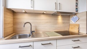 A modern kitchen with a stainless steel sink, wooden backsplash, and white cabinetry. - Apartment "Gerke" with Wi-Fi (Warstein)