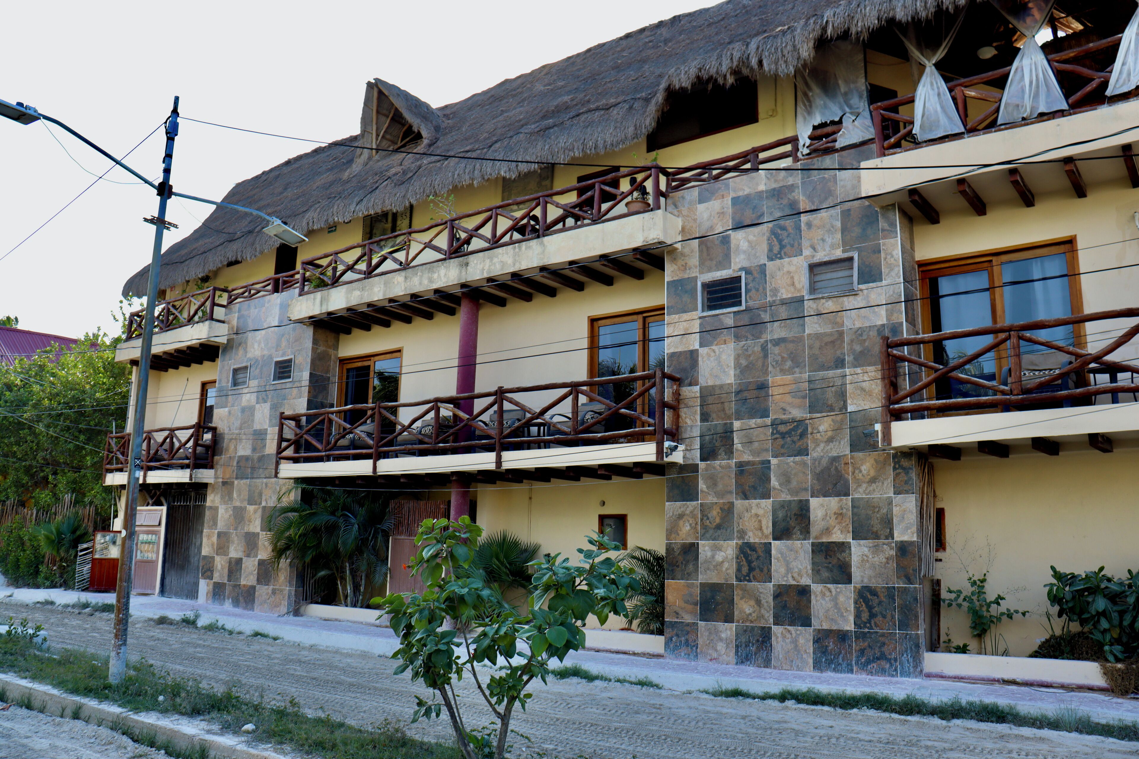 A two-story building with a thatched roof, balconies with wooden railings, and a stone facade.