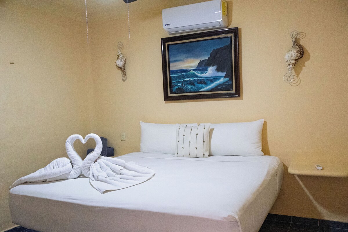 Una habitación de hotel con una cama, un cuadro de paisaje marino y un adorno en la pared.