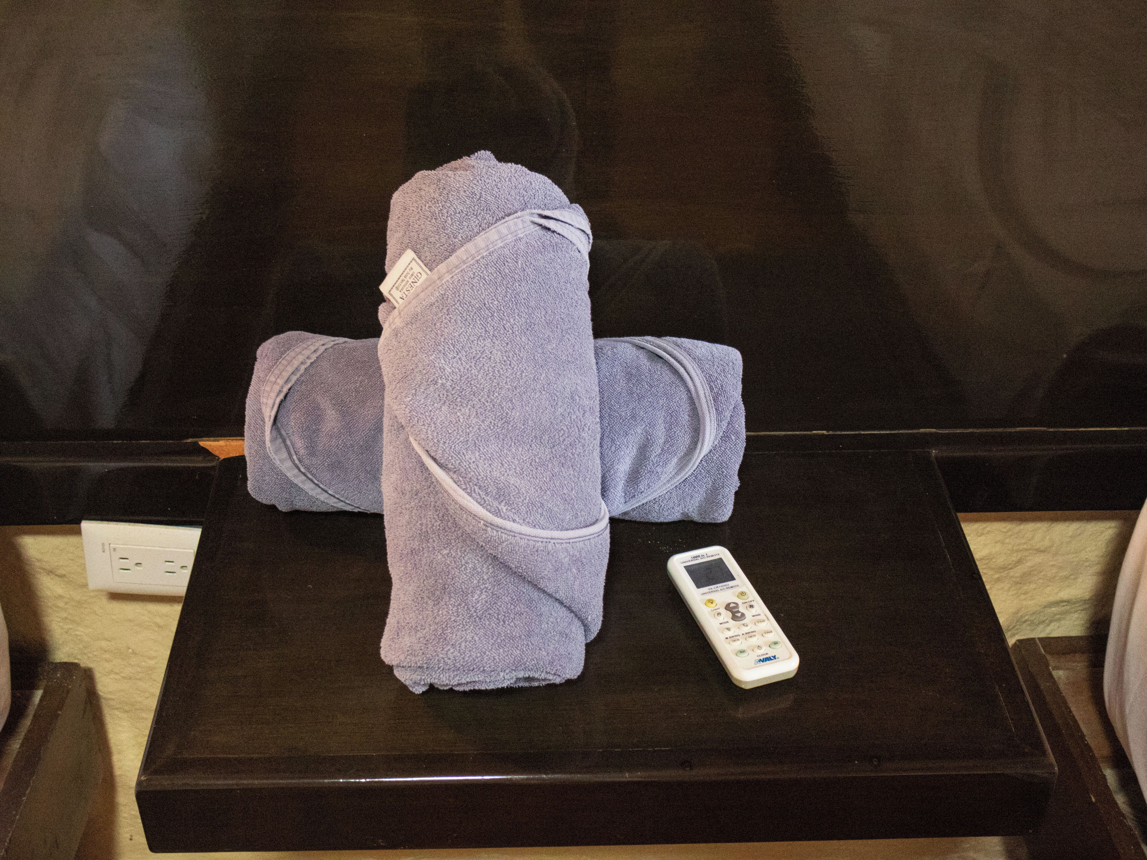 A black table with a folded towel and a remote control.