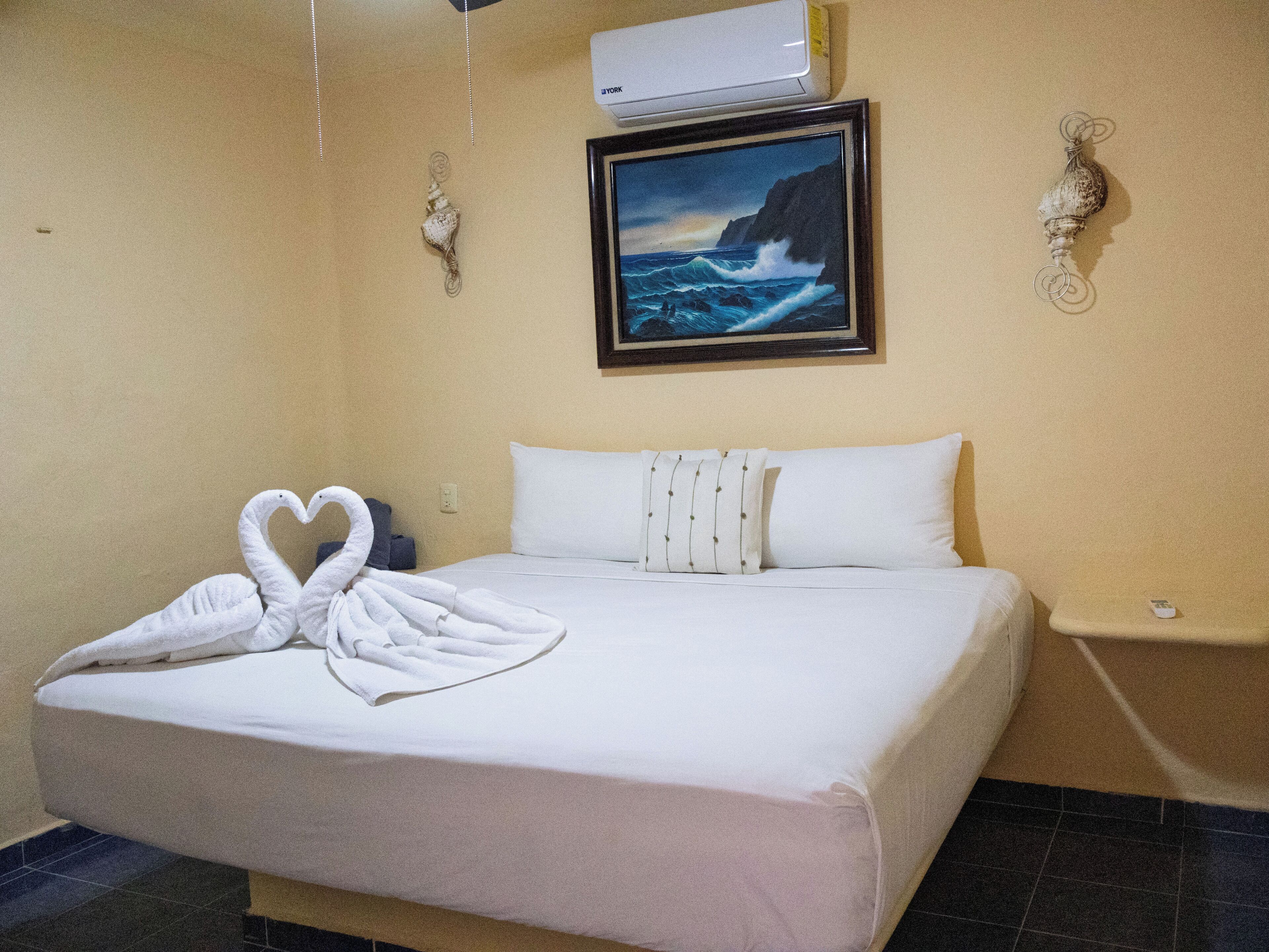 Une chambre d’hôtel avec un lit, un tableau représentant un paysage marin et un élément décoratif mural.