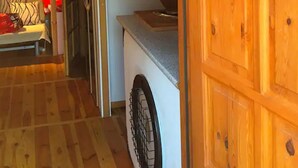 Un intérieur en bois comprenant un lave-linge, un escalier et une porte ornée d’un miroir rond.
