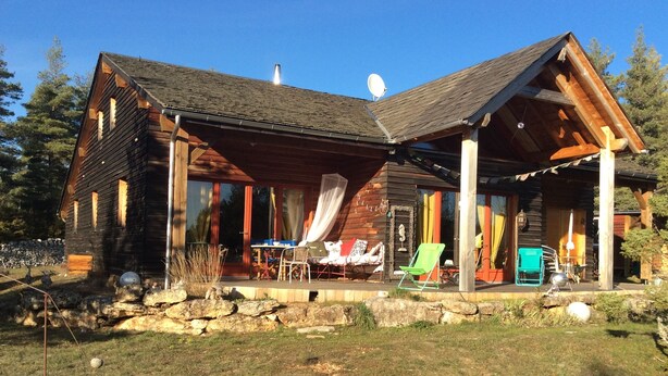 Une cabane en rondins dotée d’un porche couvert, d’un coin repas et d’un fauteuil de relaxation.