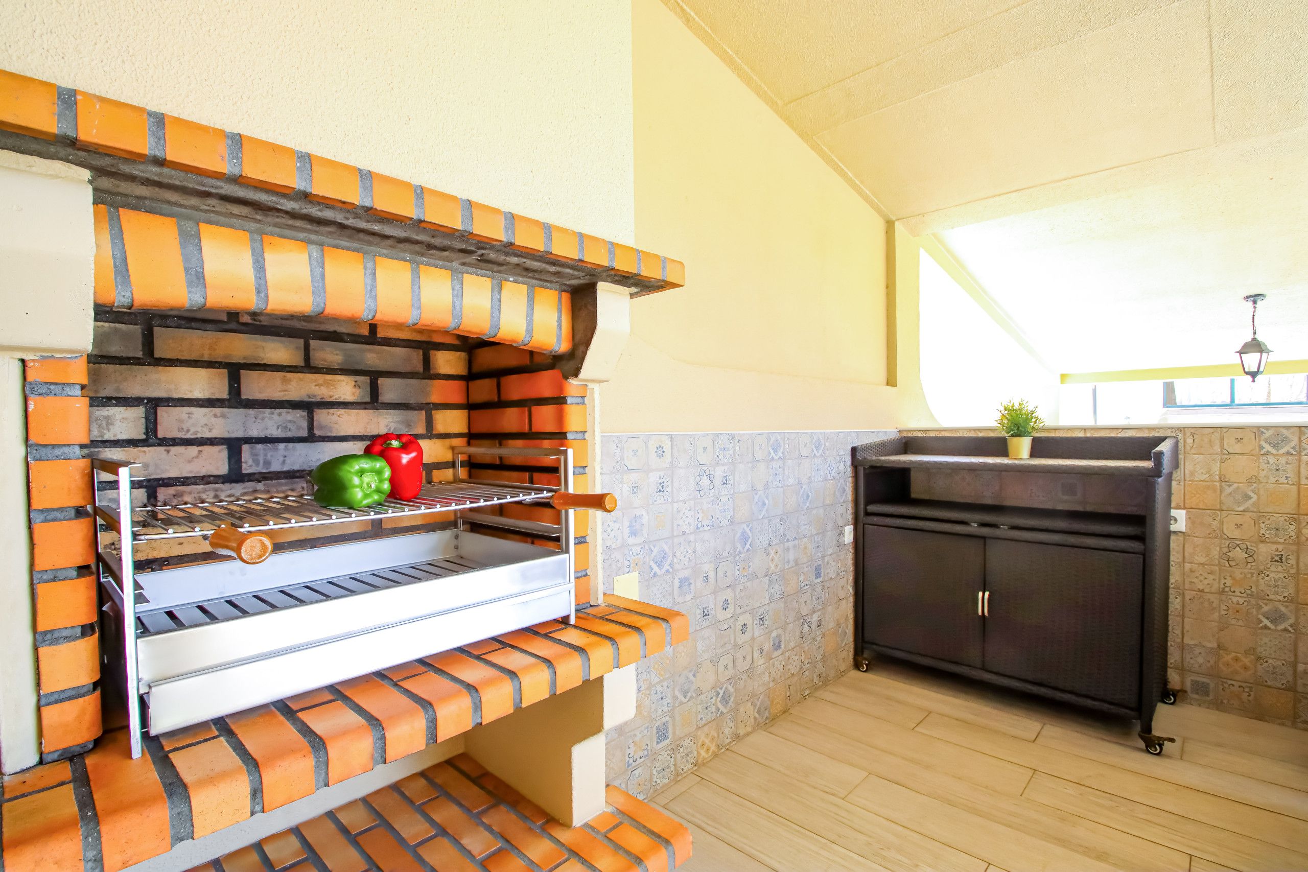 A brick oven with a shelf for cooking vegetables, a small cabinet, and a tiled backsplash.