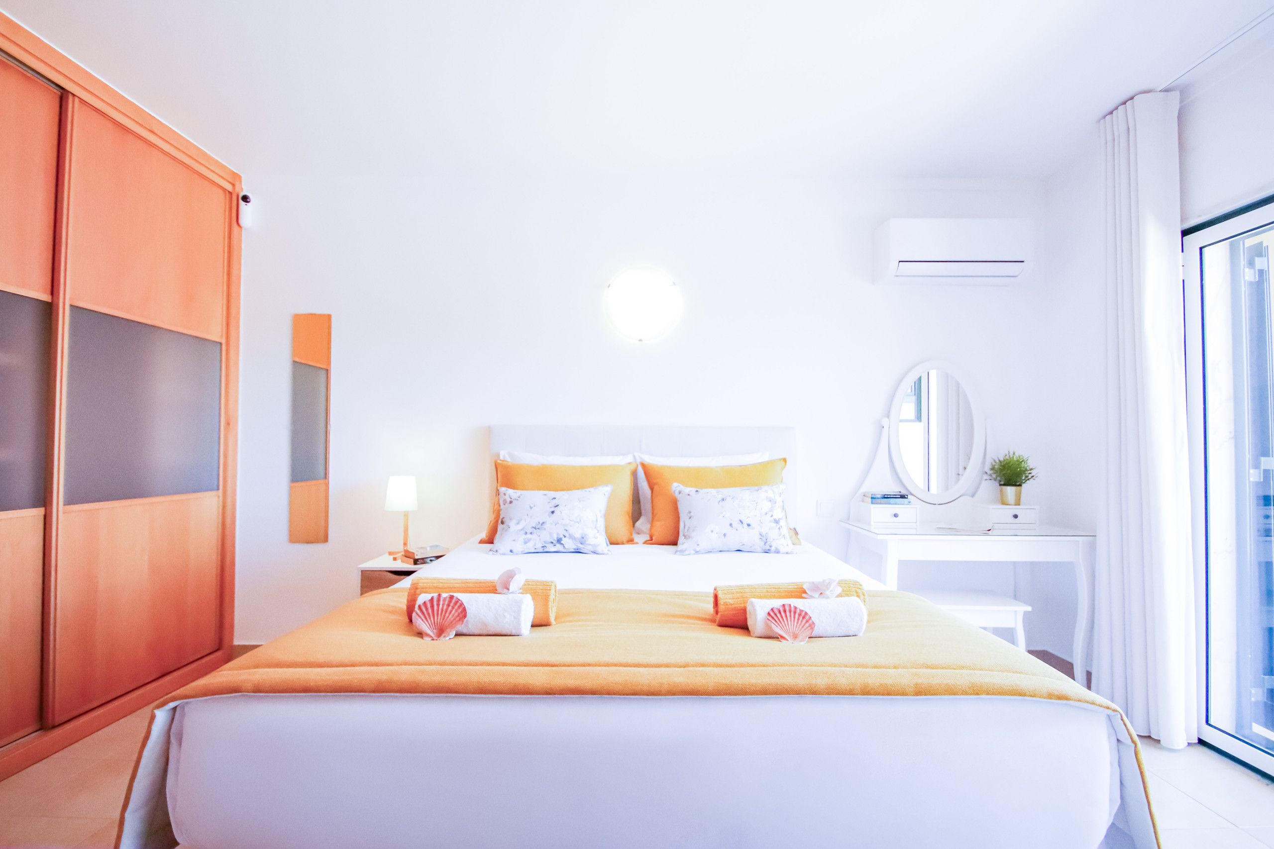 Una habitación de hotel con cama, escritorio, armario y un ventanal grande.