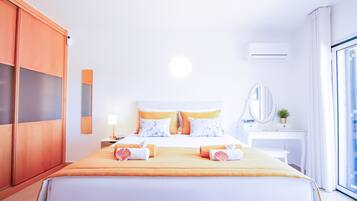 Una habitación de hotel con cama, escritorio, armario y un ventanal grande.
