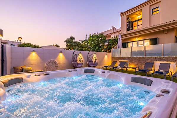 A hot tub with lounge chairs and a brick wall.