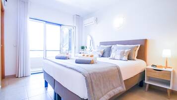Habitación de hotel con una cama grande, una mesita de noche, una lámpara y vistas al exterior.