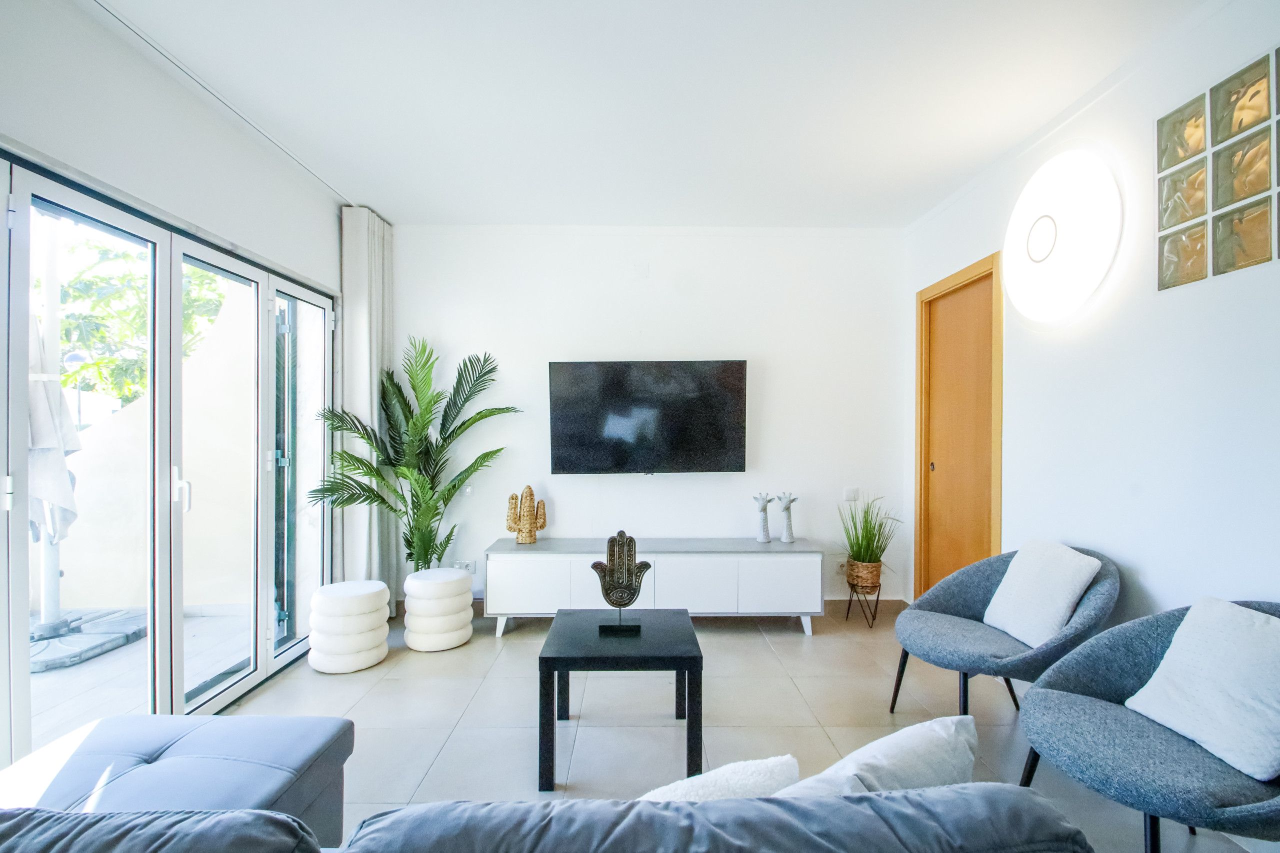 A modern living room with a sofa, a coffee table, and a TV on the wall.