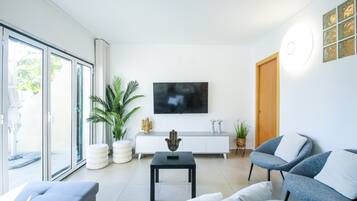 A modern living room with a sofa, a coffee table, and a TV on the wall.