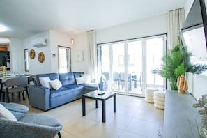 Un salon moderne avec un canapé bleu, une table basse et un coin repas avec des chaises.