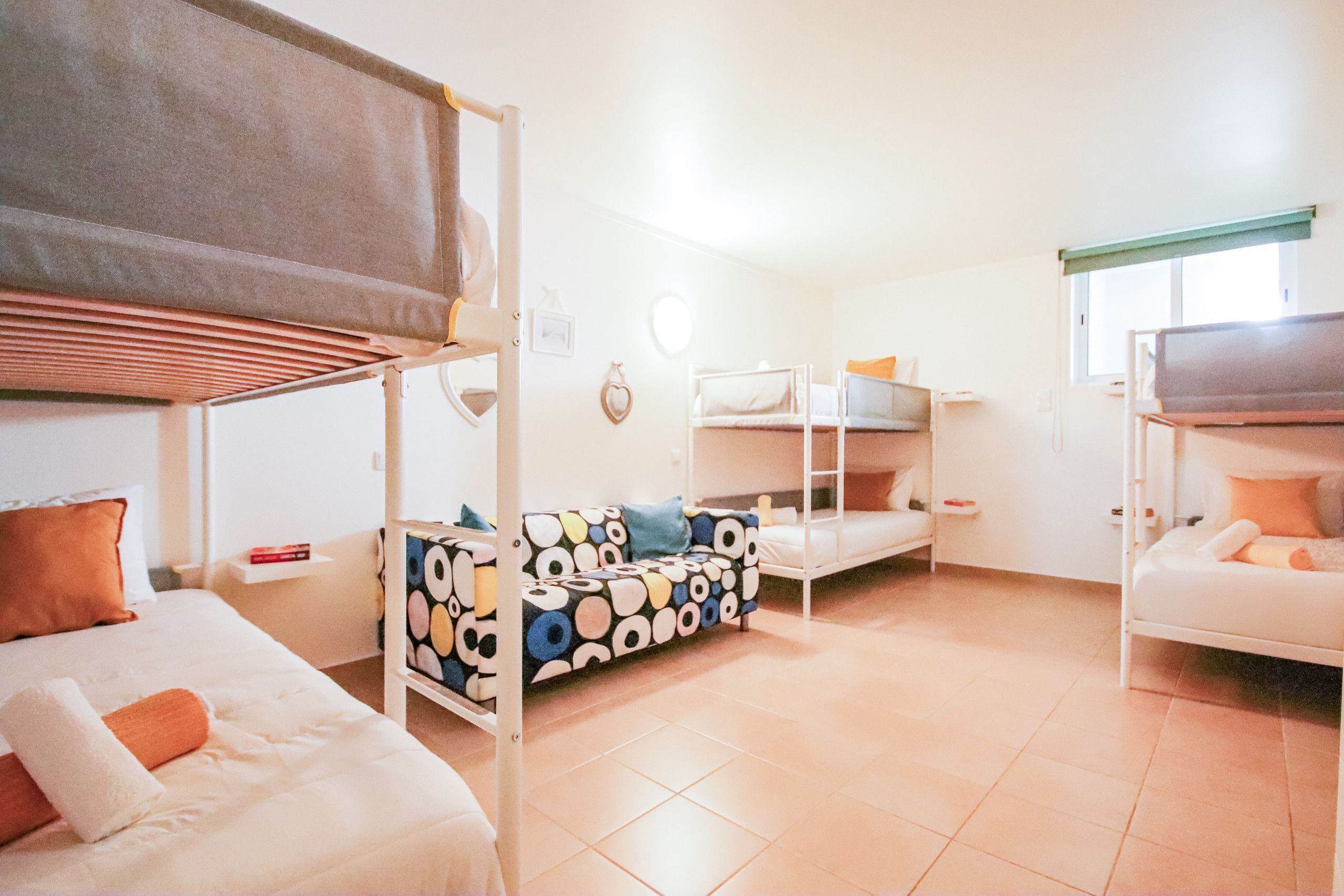 A dormitory room with bunk beds, a sofa, and a small table.