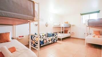 A dormitory room with bunk beds, a sofa, and a small table.