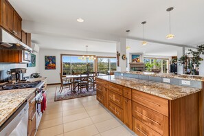 A modern kitchen with granite countertops, wooden cabinets, and a dining area with a large window.