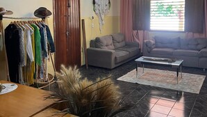 Una sala de estar con candelabro, un sofá, una mesa de centro y un perchero.