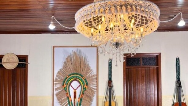 Una habitación con techo de madera, una araña, una obra de arte enmarcada, dos guitarras y una mesa con un jarrón.