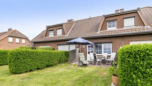 Una casa residenziale con un patio sul retro, un'area salotto coperta e un prato curato.