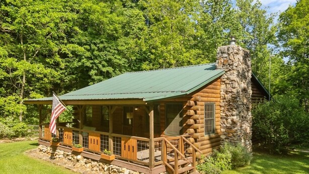 En hytte med træbeklædt facade, en stenpejs og et amerikansk flag.