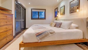 Ein Schlafzimmer mit Bett, einem Holzschrank, einem Fenster mit Jalousien und Wandleuchten.