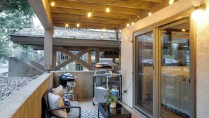 Eine Terrasse im Freien mit Grill, Sitzgelegenheiten und Blick auf die Straße.