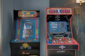 Twee speelautomaten, waarvan één 'Pac-Man' en de ander 'NBA Jam' heeft, met zichtbare spelbeelden en bedieningselementen.