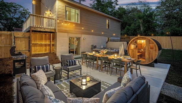 Ein modernes Haus mit Terrasse, Gartenmöbeln und einer Holzbott substruktur.