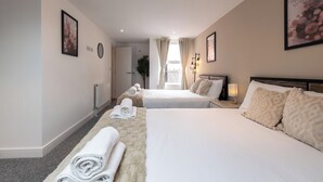 Ein Hotelzimmer mit zwei Betten, einem großen Fenster, einer Pflanze und Blick auf die Stadt.