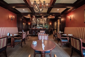 A bar area with a television, bar stools, and a counter. - Beaumont Inn (Harrodsburg)