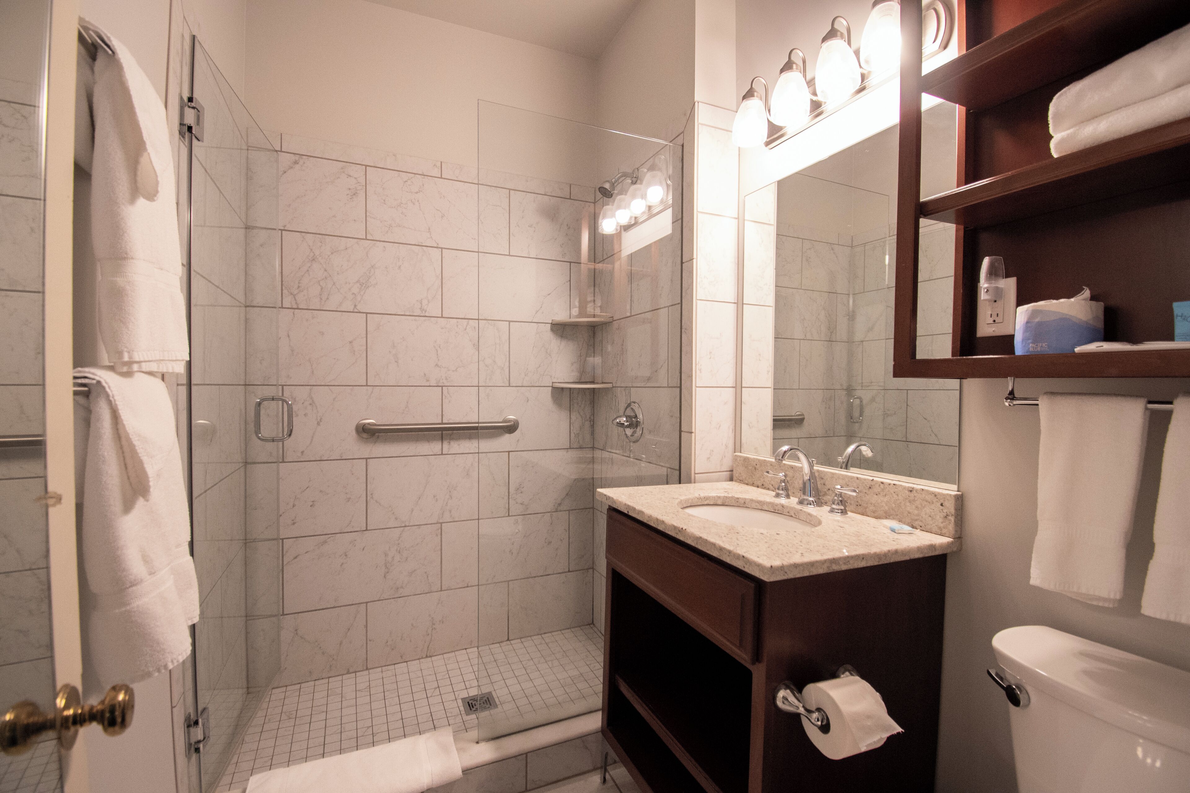 A bathroom with a glass-enclosed shower, a vanity with a sink, and a toilet.
