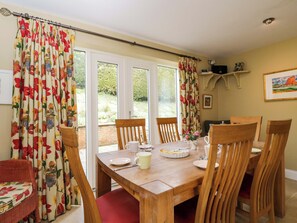 Un comedor con una mesa de madera, sillas y un ventanal con cortinas.