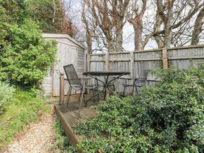 A wooden deck with a table and chairs, surrounded by greenery and a wooden fence. - Ormiston House (Pewsey)