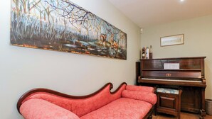 A room with a red sofa, a wooden piano, and a large abstract painting on the wall. - Ormiston House (Pewsey)