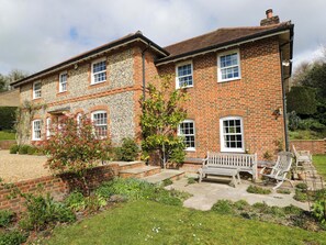 A two-story brick house with a garden, a bench, and a pathway leading to the entrance. - Ormiston House (Pewsey)