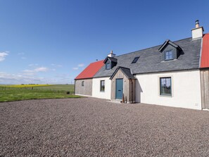 Ein Haus mit Kiesweg, rotem Dach und einem kleinen Anbau mit blauer Tür.