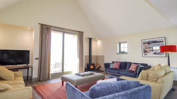 A spacious living room with a television, sofas, a fireplace, and a large window.