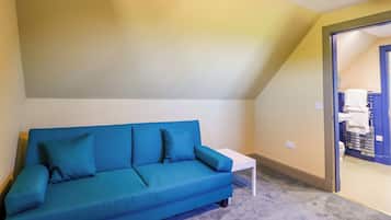 A room with a blue sofa, a white table, and a ceiling light fixture.