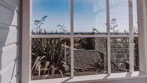 Une fenêtre donnant sur un paysage côtier, avec une végétation luxuriante et une ligne de côte visible au loin.