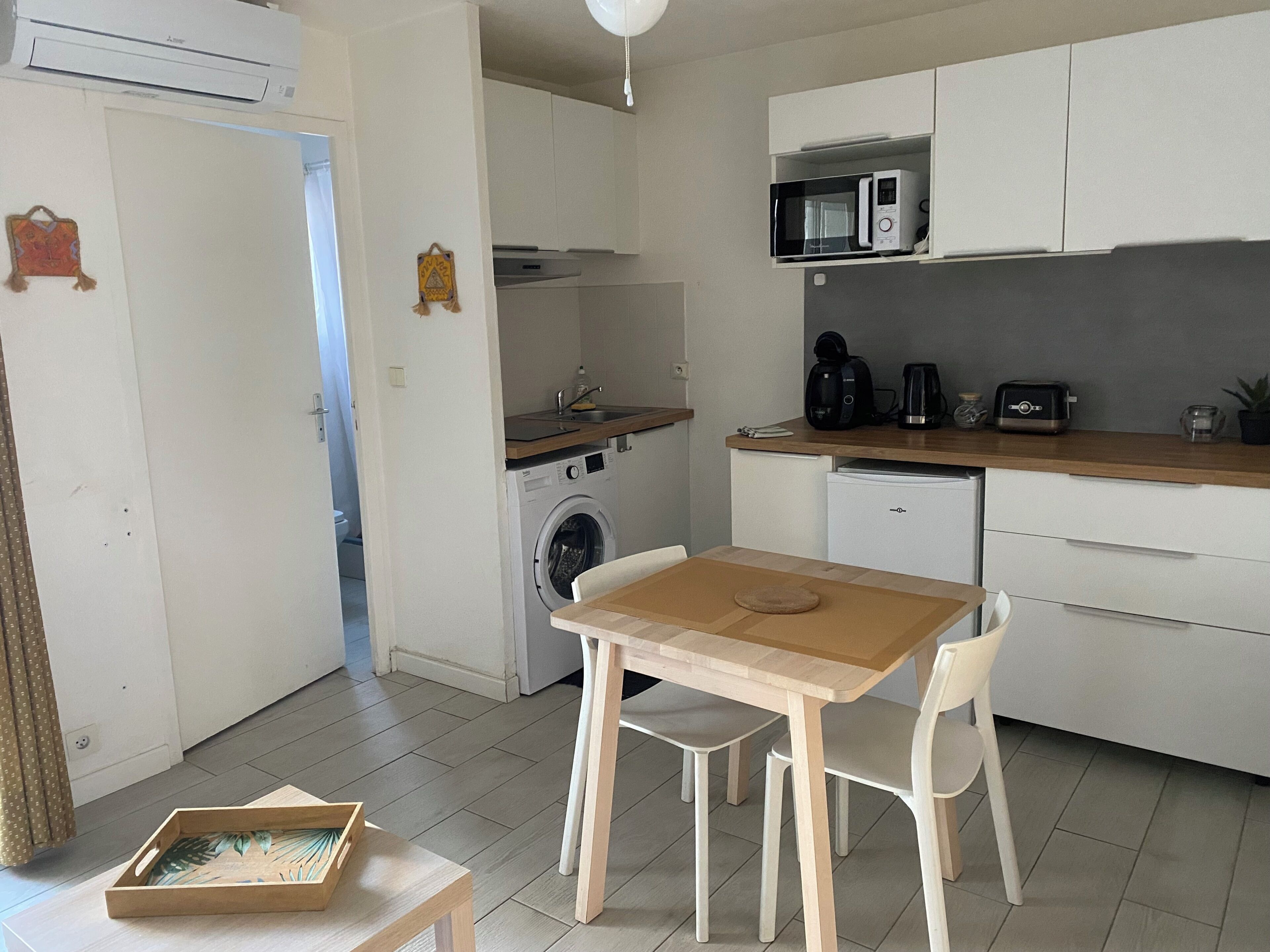 Cocina compacta equipada con lavadora, microondas y cafetera.