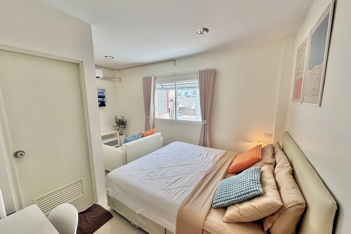 Une chambre d’hôtel comprenant un lit, un bureau, une chaise, un radiateur, une fenêtre avec des rideaux et un tableau accroché au mur.