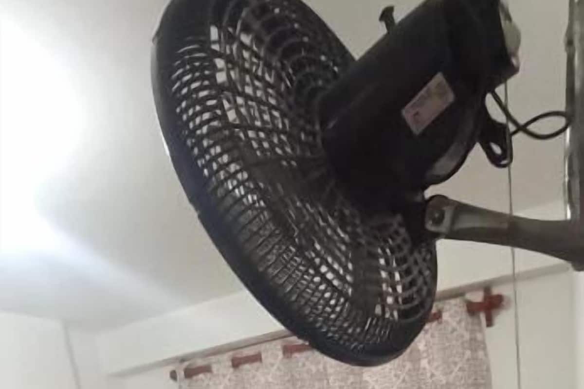 Une chambre d’hôtel avec un lit, une table de chevet, une lampe et un ventilateur de plafond.