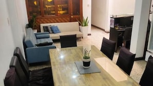 Een eethoek met een houten tafel, zwarte stoelen en een potplant.