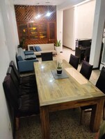 Un comedor con mesa de madera, sillas negras y una planta en maceta.
