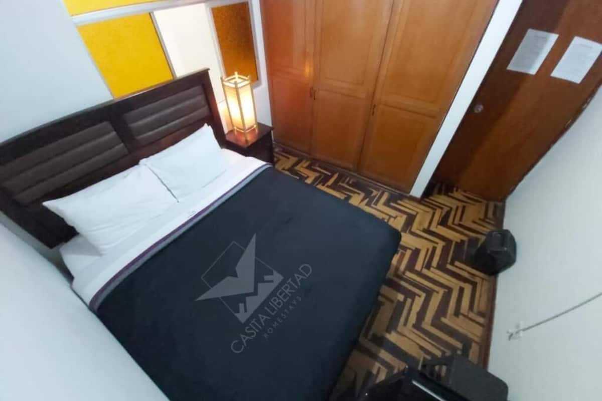 Une chambre d’hôtel avec un lit, une table de chevet, une lampe et une armoire.