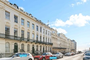 A row of classic European-style buildings with uniform architecture, a clear sky, and parked cars along the street. - Oriental Eight | By My Getaways (Brighton)