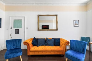 A room with a sofa, two armchairs, a mirror, and a door with a window. - Oriental Eight | By My Getaways (Brighton)