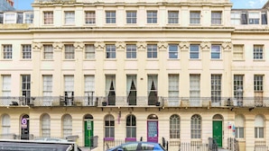 A multi-story building with a symmetrical facade, large windows, and a green door. - Oriental Nine | By My Getaways (Brighton)