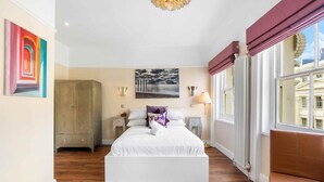 Een slaapkamer met een groot bed, een kledingkast, een nachtkastje, een lamp en een raam met uitzicht.