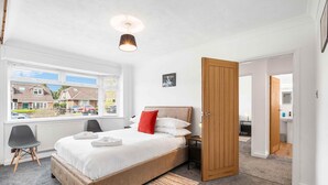 Ein Schlafzimmer mit Bett, Fenster, Tür und Blick nach draußen.
