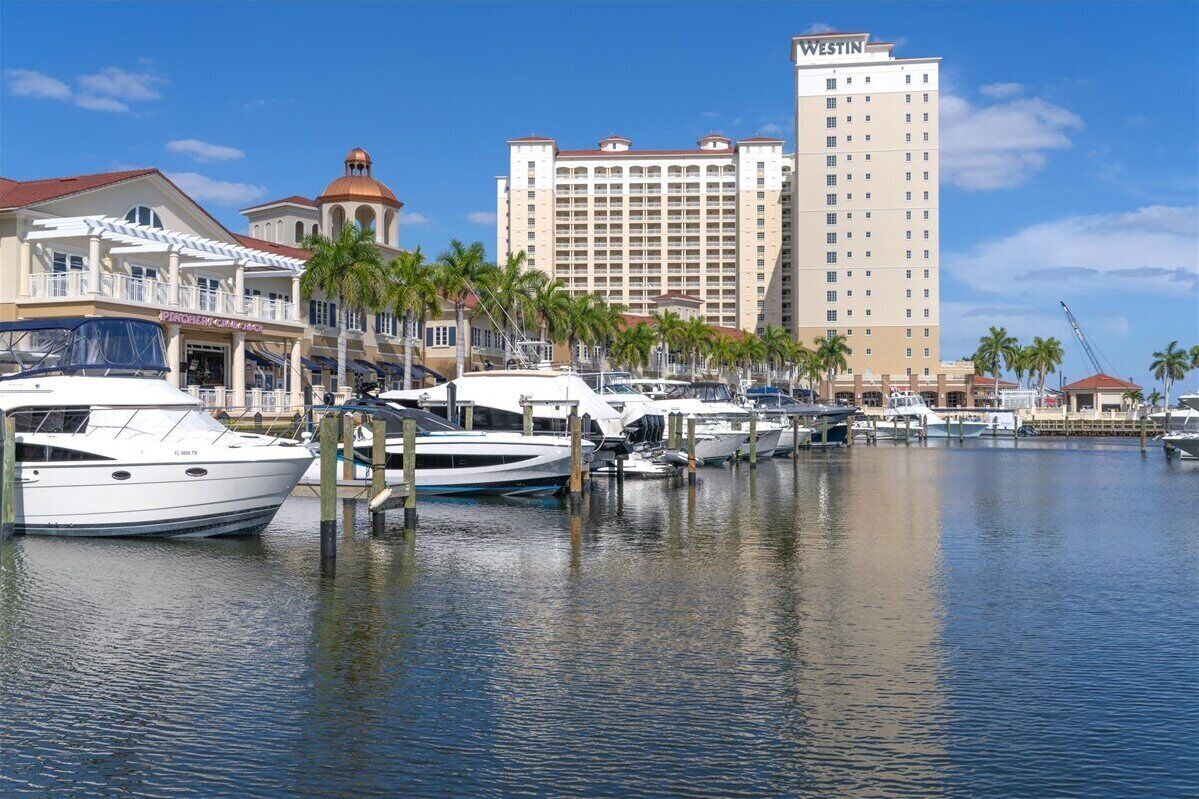 A marina with boats docked, a hotel named 'Westin' in the background, and a building with a dome and palm trees in the foreground.